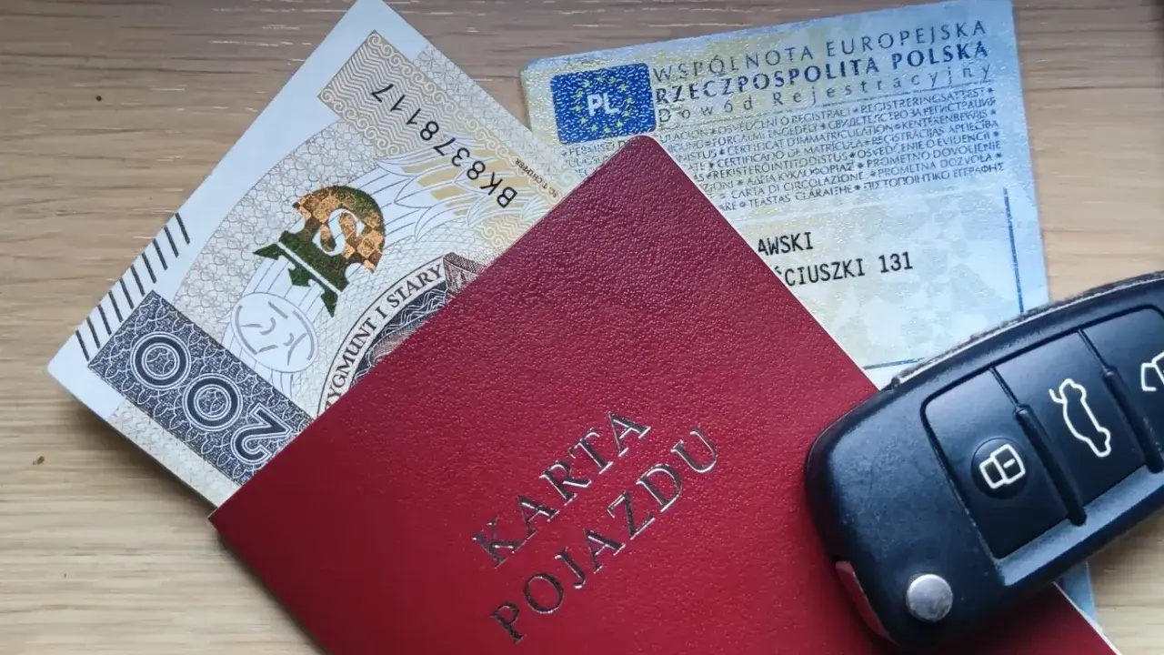 Karta pojazdu, dowód rejestracyjny, pieniądze i kluczyki samochodowe na drewnianym tle.