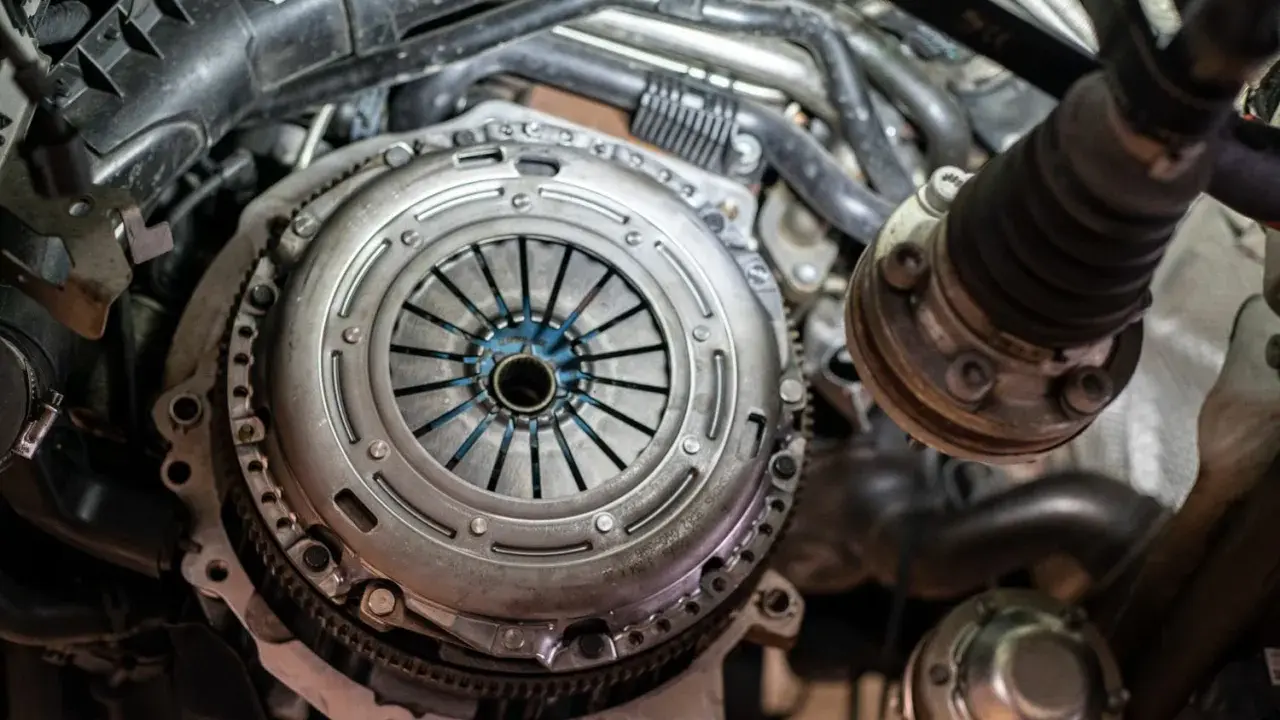 Zbliżenie na mechanizm sprzęgła samochodowego z widocznymi elementami silnika.