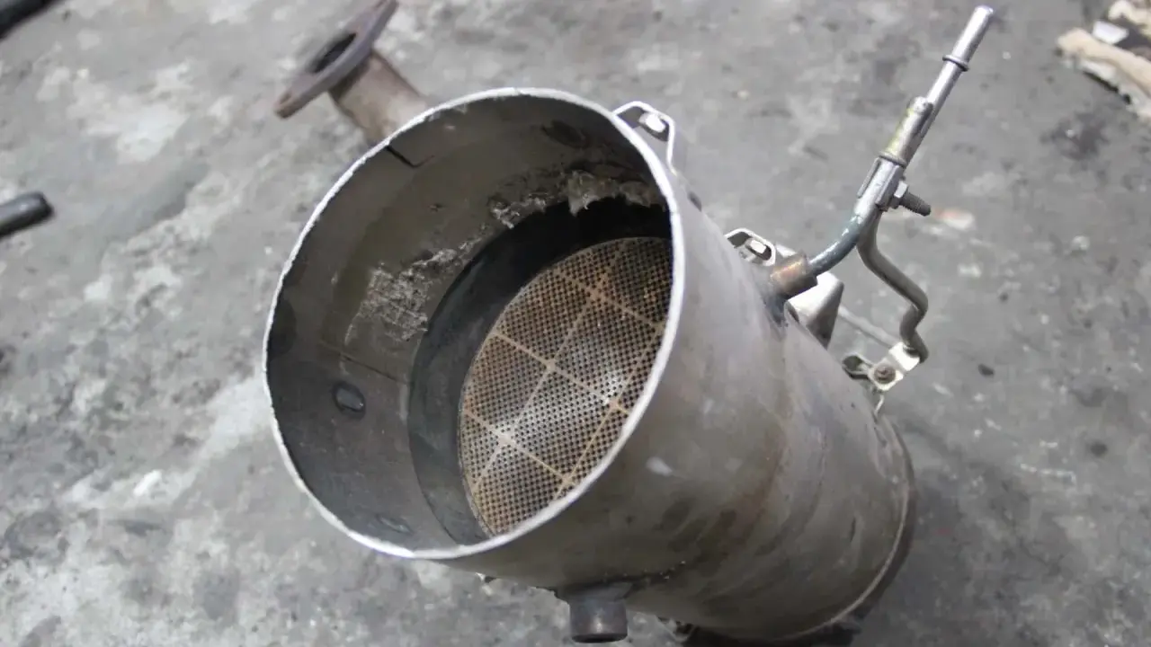 Filtr DPF z widocznym wkładem ceramicznym i rurką.