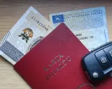 Karta pojazdu, dowód rejestracyjny, pieniądze i kluczyki samochodowe na drewnianym tle.