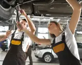 Mechanicy pracujący pod samochodem, wymiana części.