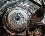 Zbliżenie na mechanizm sprzęgła samochodowego z widocznymi elementami silnika.