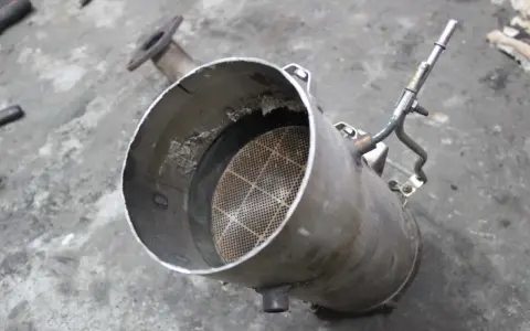 Filtr DPF z widocznym wkładem ceramicznym i rurką.