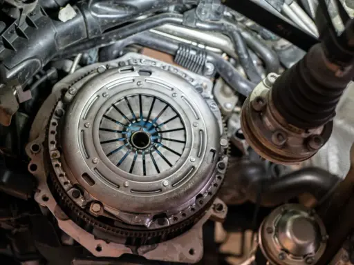 Zbliżenie na mechanizm sprzęgła samochodowego z widocznymi elementami silnika.
