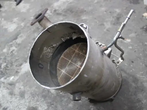 Filtr DPF z widocznym wkładem ceramicznym i rurką.