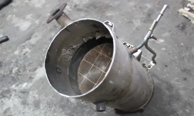 Filtr DPF z widocznym wkładem ceramicznym i rurką.